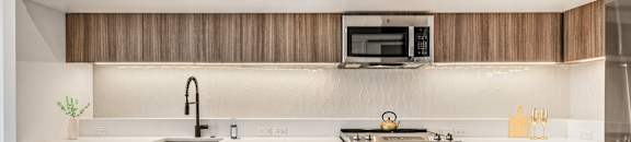 A modern kitchen with white cabinets and a wooden backsplash.