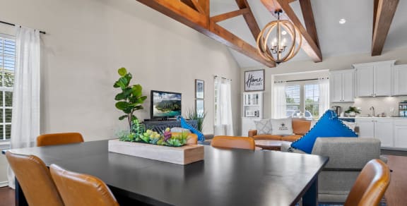 a dining area with a table and chairs and a living room in the background