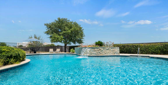 a pool with a waterfall and a tree in the background