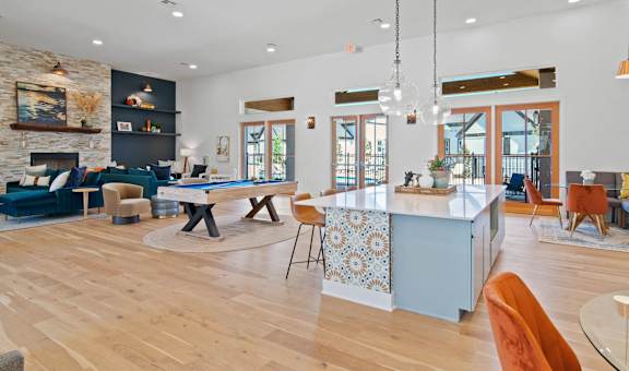 a living room with a ping pong table and a kitchen