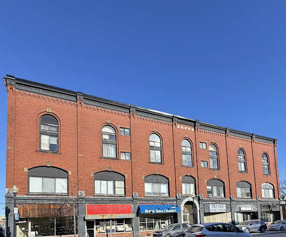 A red brick building with a white car parked in front of it.