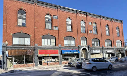 A red brick building with a white car parked in front of it.