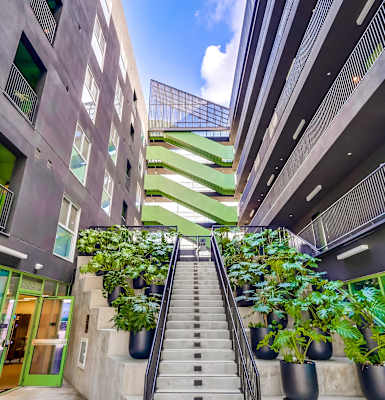 A staircase with a metal railing leads up to a green area.