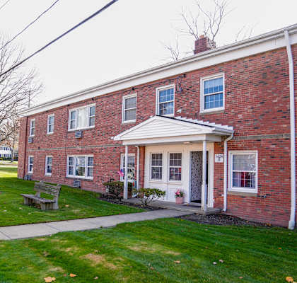 the front of a brick building with a sidewalk and grass