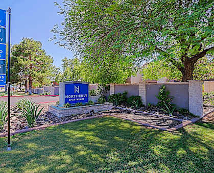 A sign for Northernly Accommodations is displayed in front of a tree and a building.
