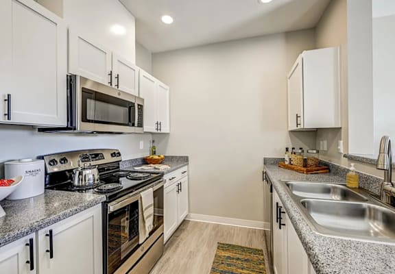 A kitchen with white cabinets and a granite countertop.