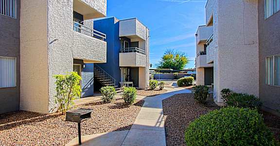 a pathway between two buildings with a blue sky in the background