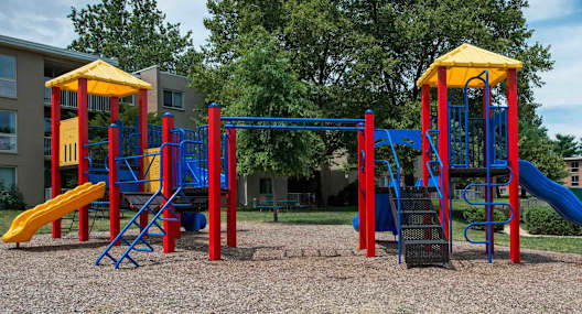 A playground with a blue and yellow slide and a red and yellow structure.