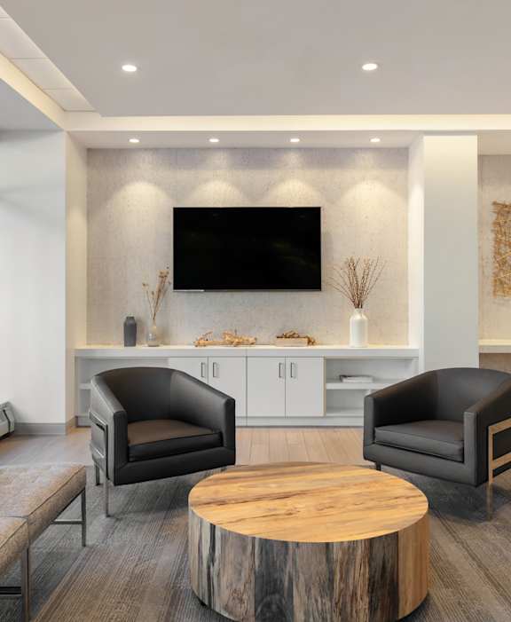 A modern living room with a grey sofa, a black leather chair, and a wooden coffee table.