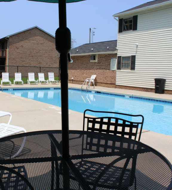 a swimming pool with chairs and tables next to a house