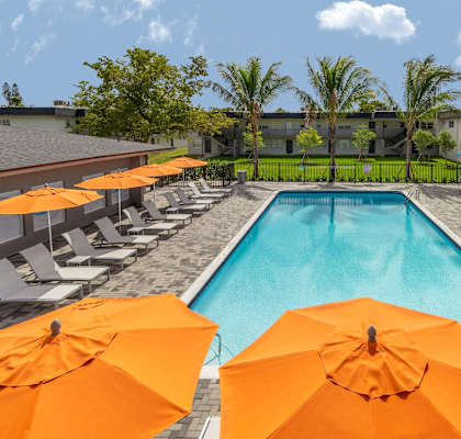 A pool surrounded by orange umbrellas and chairs.