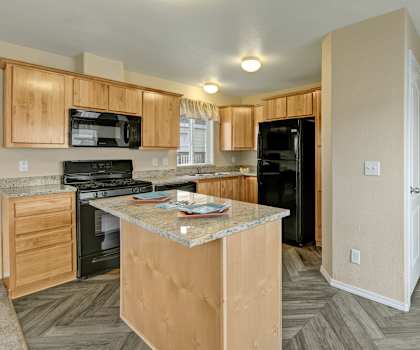 A kitchen with black appliances, marble countertops, and wooden cabinets with decorations at Four Seasons Apartment Homes. 