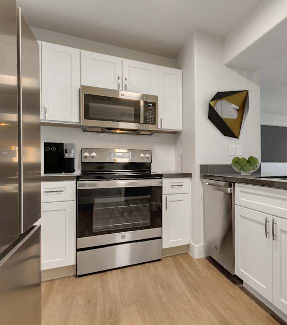 an open kitchen with stainless steel appliances and white cabinets at Bella Terra Apartments, Henderson, 89012