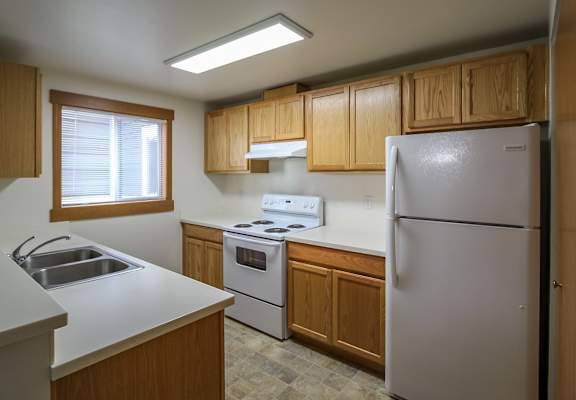 A kitchen with a white refrigerator, sink, and stove.