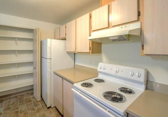 A kitchen with a white stove and wooden cabinets.