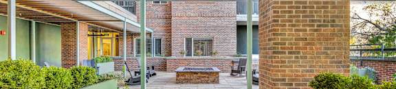 a covered porch with a brick wall and a fire pit