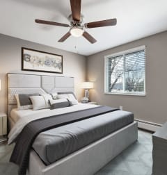the master bedroom has a king sized bed and a ceiling fan