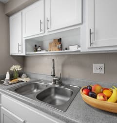 a kitchen sink with a bowl of fruit on the counter