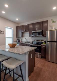 a kitchen with stainless steel appliances and a counter with three stools