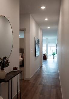 a hallway with a mirror and a table with a plant