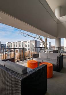 a balcony with couches and orange tables and a building in the background
