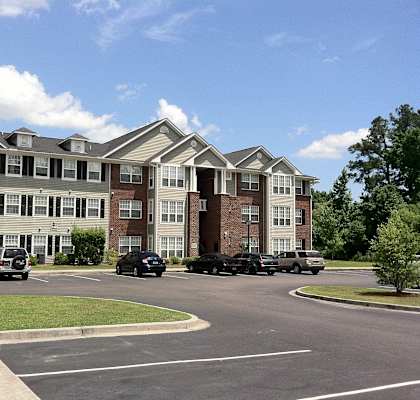 an apartment building with cars parked in a parking lot