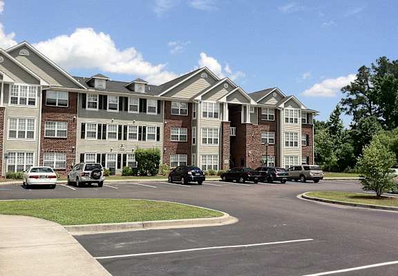 an apartment building with cars parked in a parking lot