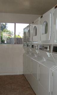 a laundry room with white washers and dryers and a window