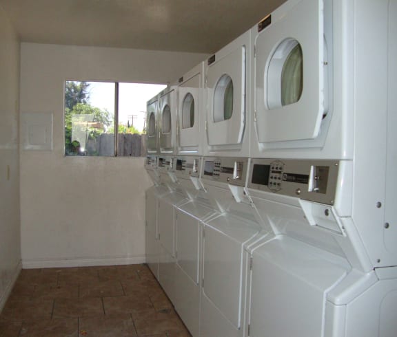 a laundry room with white washers and dryers and a window