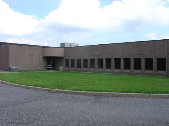 A large grey building with a green lawn in front.