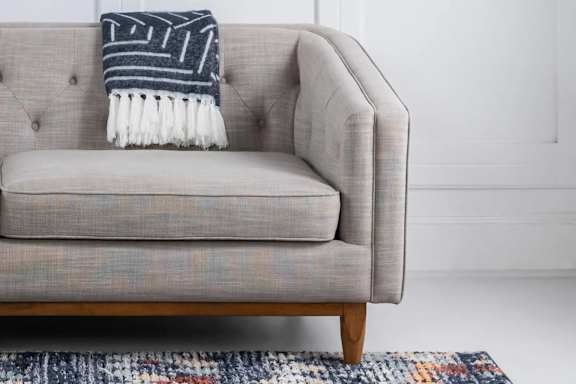 A grey couch with a striped throw blanket on it.