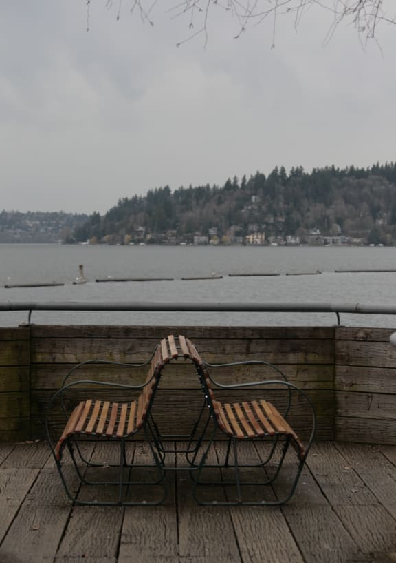 a couple of benches on a wooden deck next to a body of water