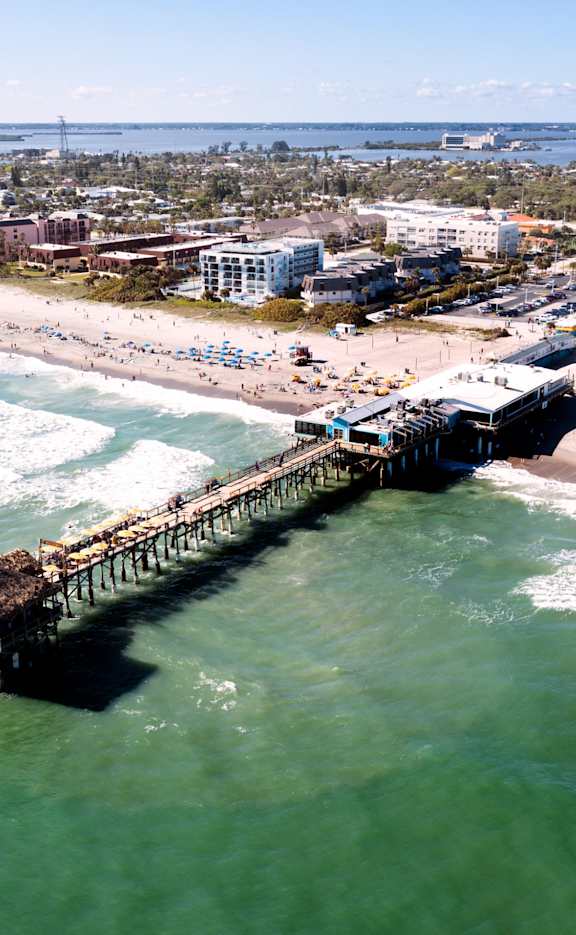 A pier extends into the ocean on a sunny day.