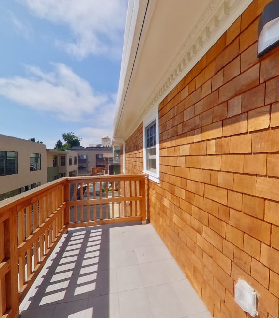 a balcony with a wooden railing and a blue sky