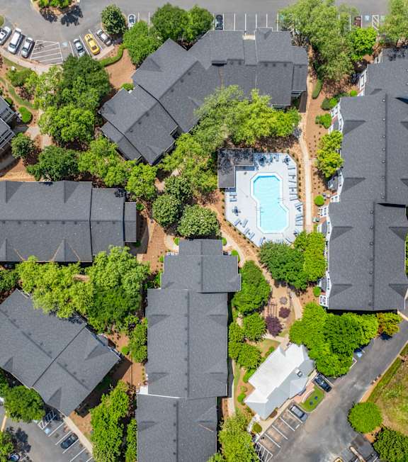 A bird's eye view of a residential area with houses, a swimming pool, and a parking lot.