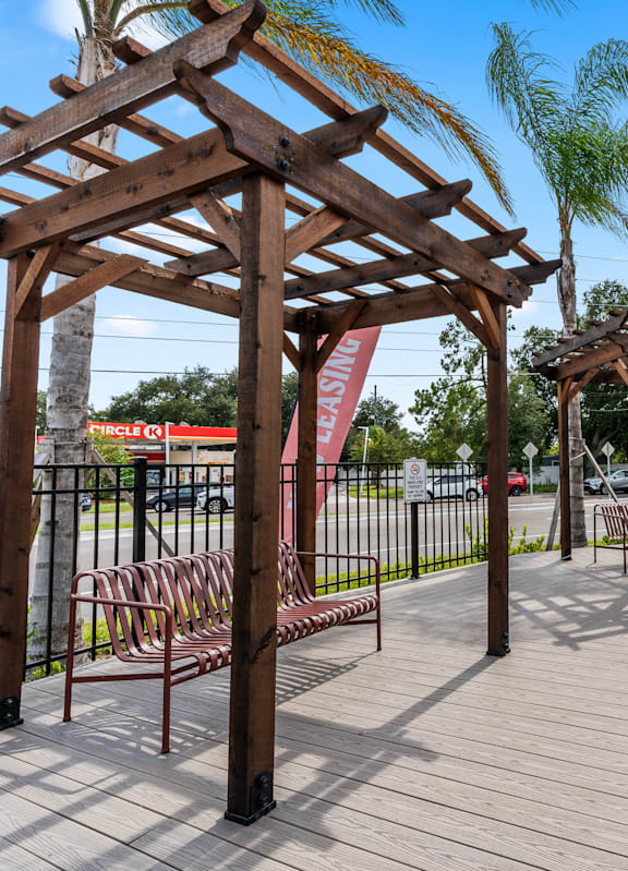 A wooden pergola with benches is situated in a park. at The Teale Siesta Lago in Kissimmee, FL, 34746