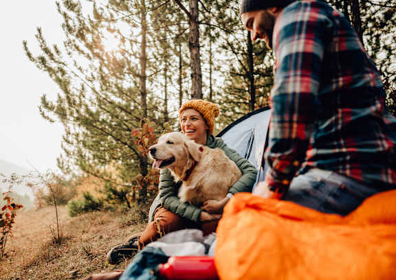 A man and woman sitting in a tent with a dog.