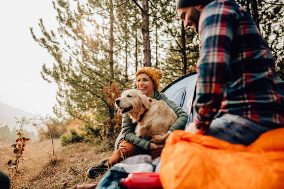 A man and woman sitting in a tent with a dog.
