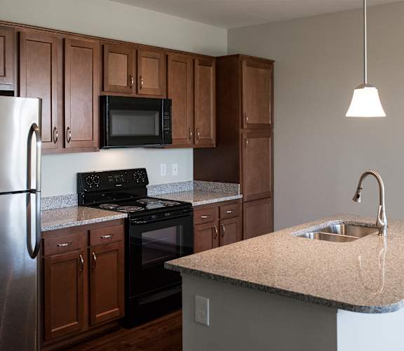 A kitchen with brown cabinets and a stainless steel refrigerator.