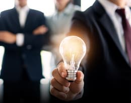 business professionals in suits holding a light bulb in their hand representing growth and innovation