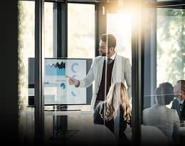 a business professional in an office presenting data on a screen to a group of people representing quality and results driven