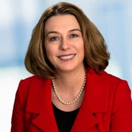 a woman wearing a red jacket and a pearl necklace