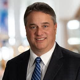 a man in a suit and tie smiling at the camera