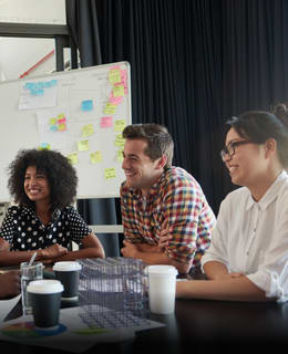 a group of people sitting around a table talking representing collaboration