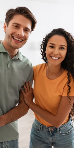 a man and woman smiling with their arms around each other