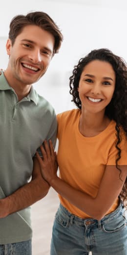 A man and a woman are standing close together, smiling.