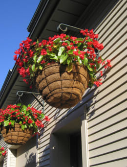 two baskets of red flowers on the side of a building