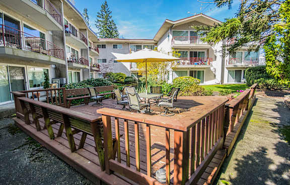 a wooden deck with a table and chairs and an umbrella