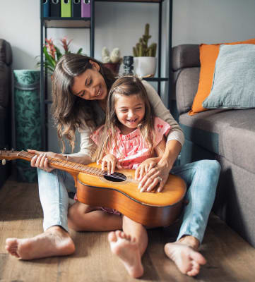 Mother and daughter playing guitar on apartment floor  at Arrive Los Carneros II, Goleta