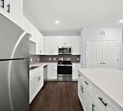 a renovated kitchen with white cabinets and stainless steel appliances
